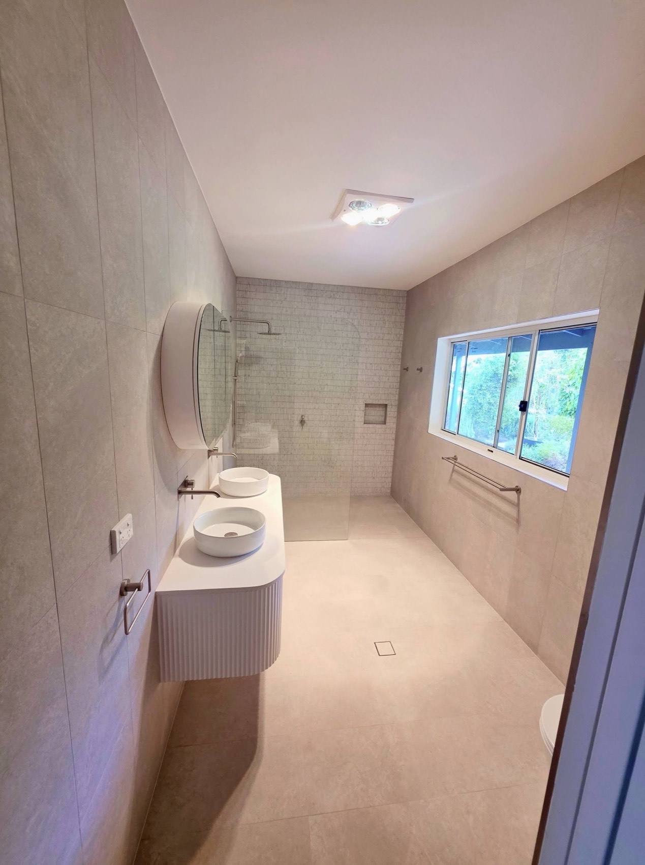 A finished ensuite with large-format wall tiles, a fluted vanity and a walk-in shower