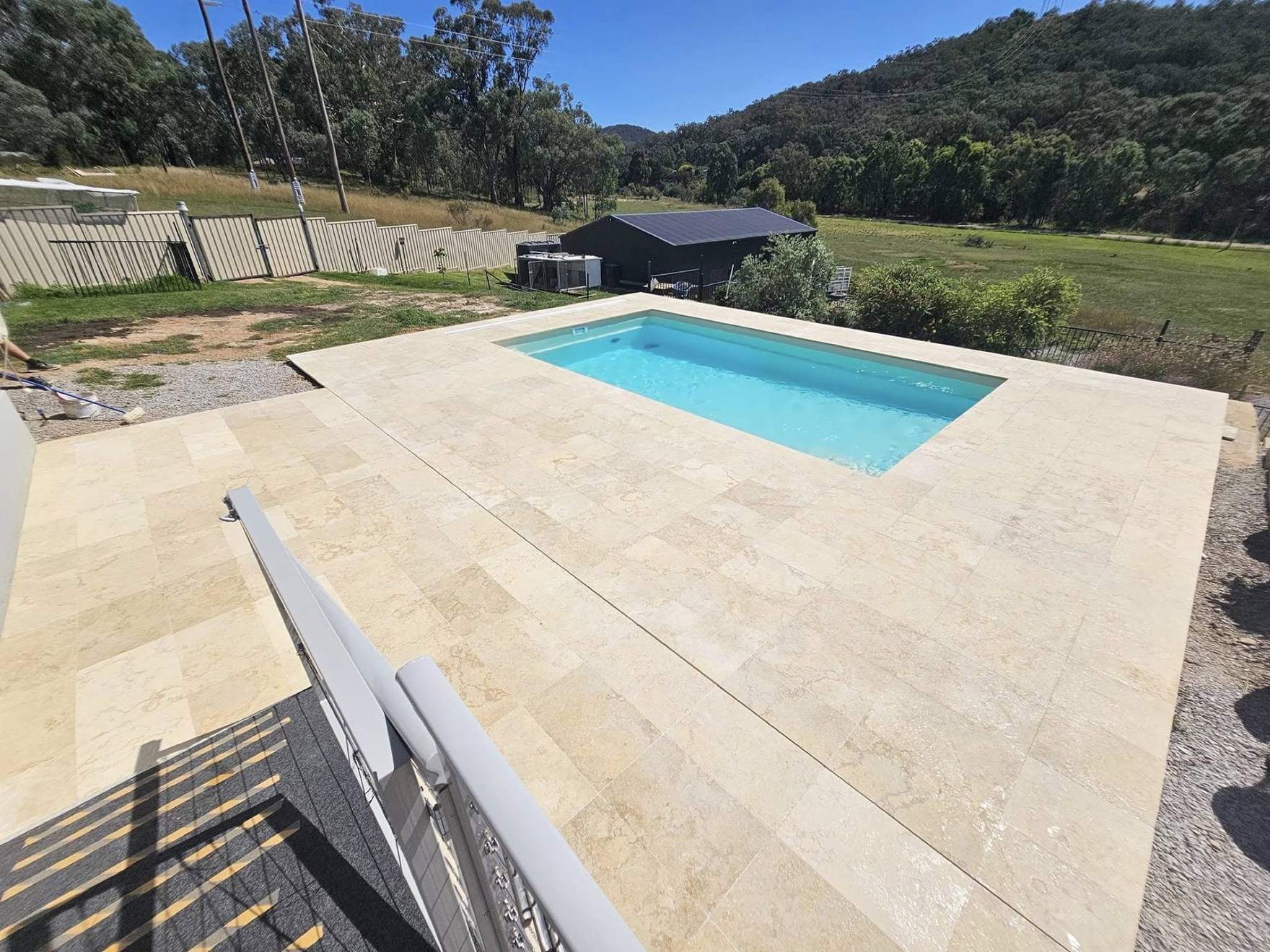 A pool with a fresh stone surround and hills in the distance