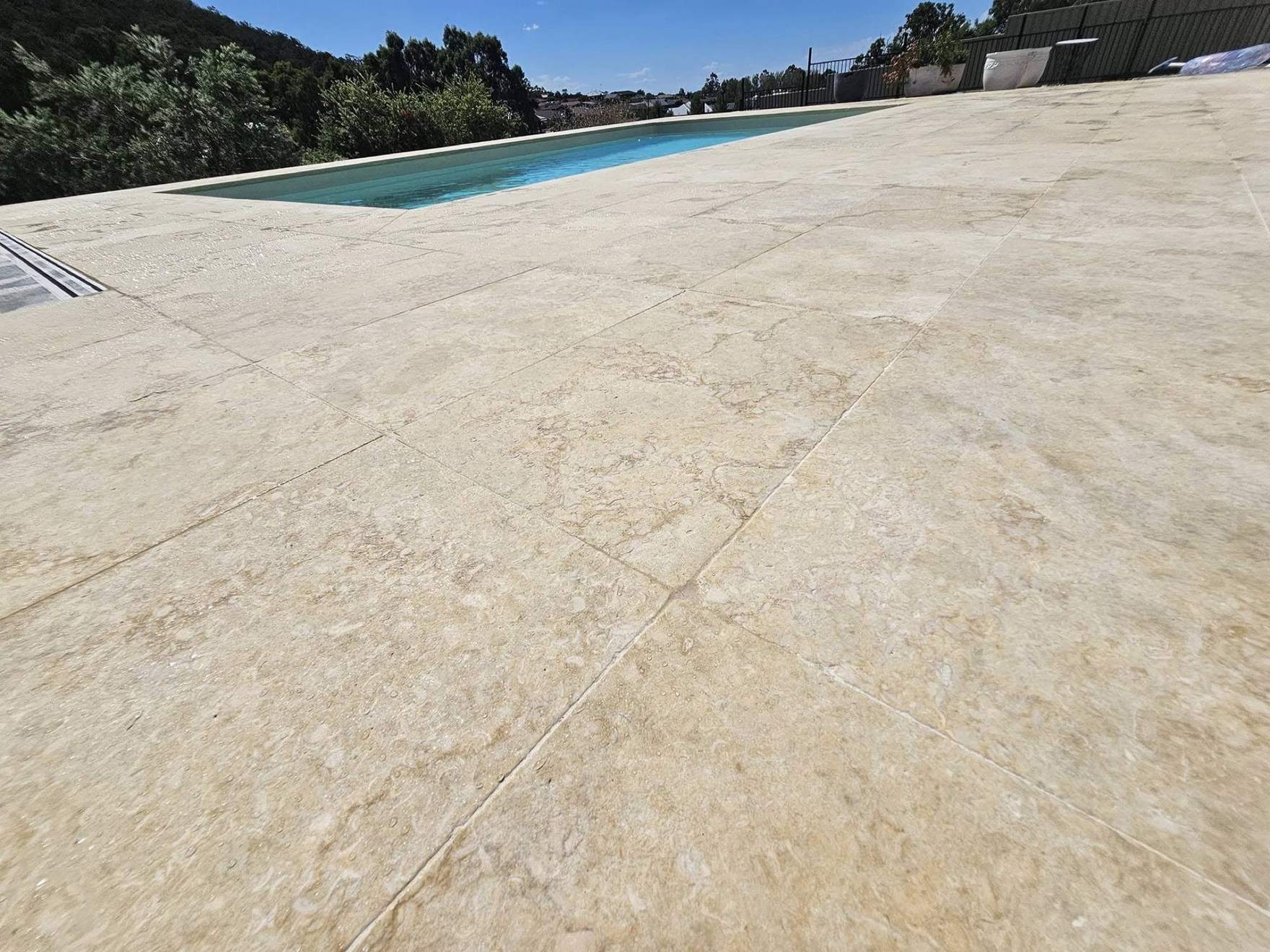 A close view of a travertine pool deck laid in a running pattern