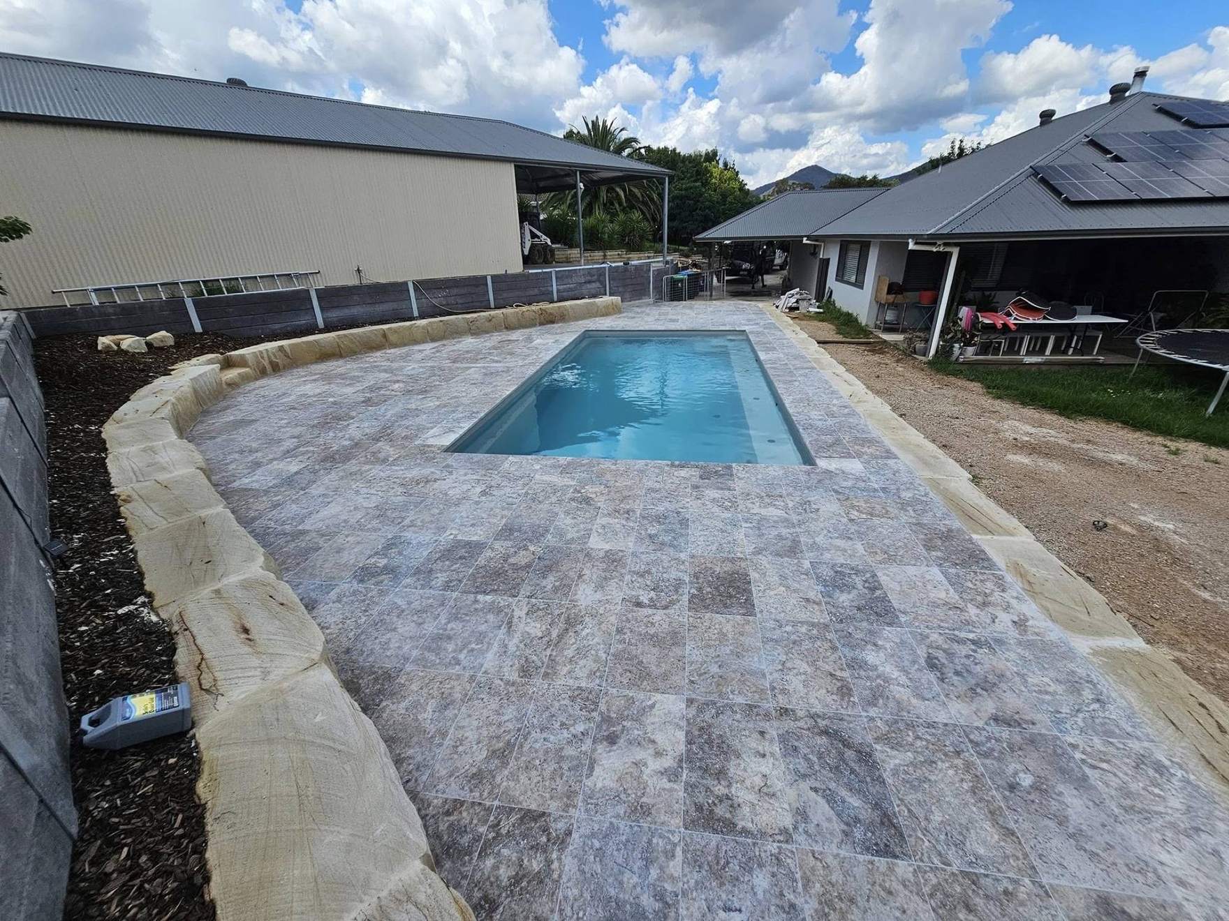 A wide travertine pool deck running out to the water's edge