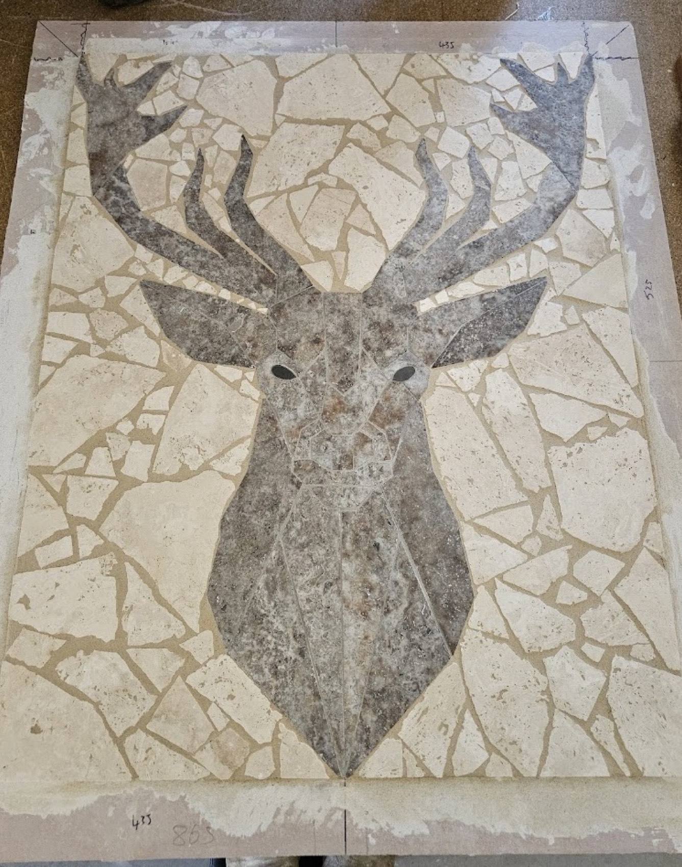 A stag cut by hand from travertine and set into a stone panel