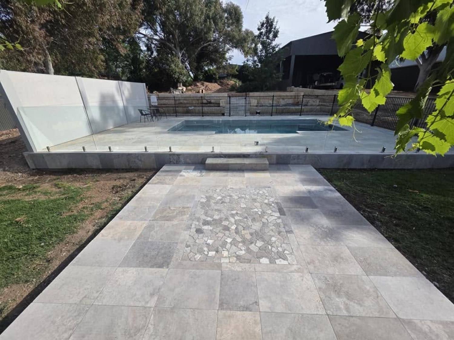 A stone path with a pebble inlay running beside a pool