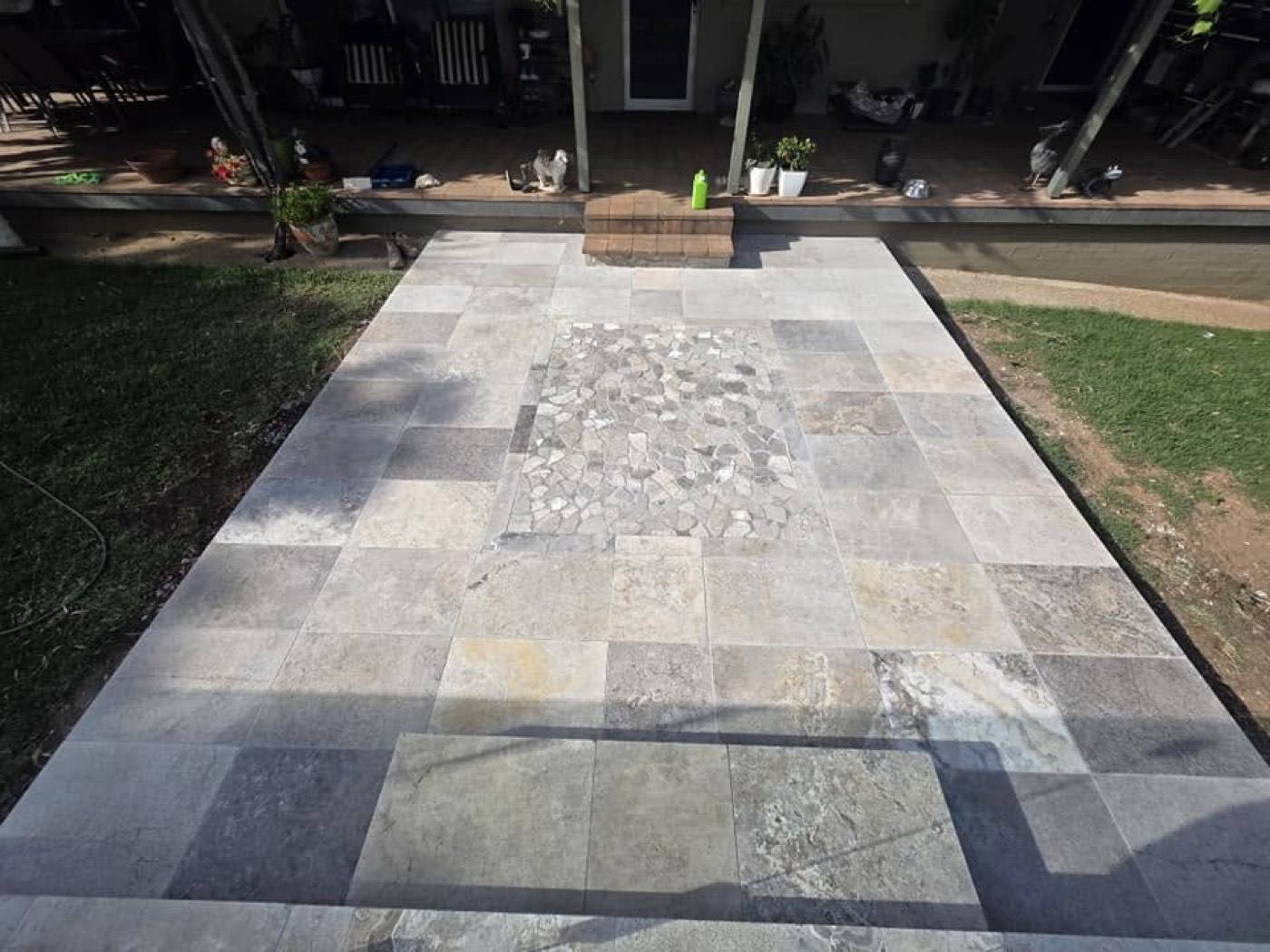 A stone path with a pebble inlay running across a lawn