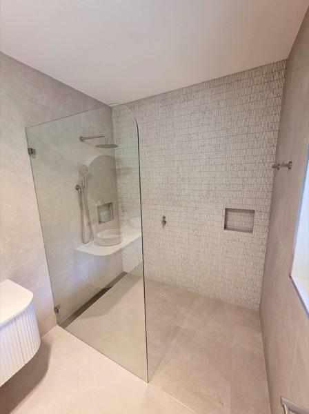 A tiled shower recess with a niche and a glass screen