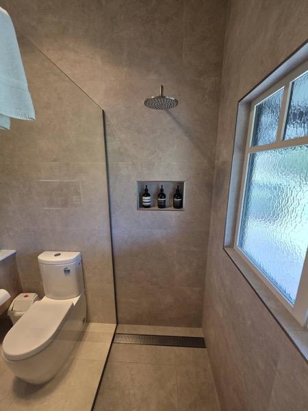 A tiled shower with a rain head, a niche and a frosted window
