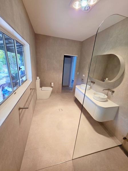 A bathroom with a wall-hung vanity and a window above the bath