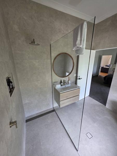 A bathroom with a corner bath, tiled walls and a window
