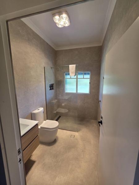 A bathroom with a wall-hung vanity, toilet and shower screen