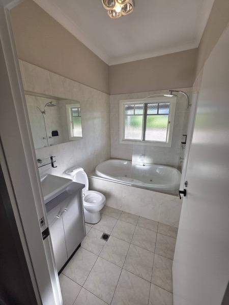 A bathroom with a corner spa bath and tiled floor