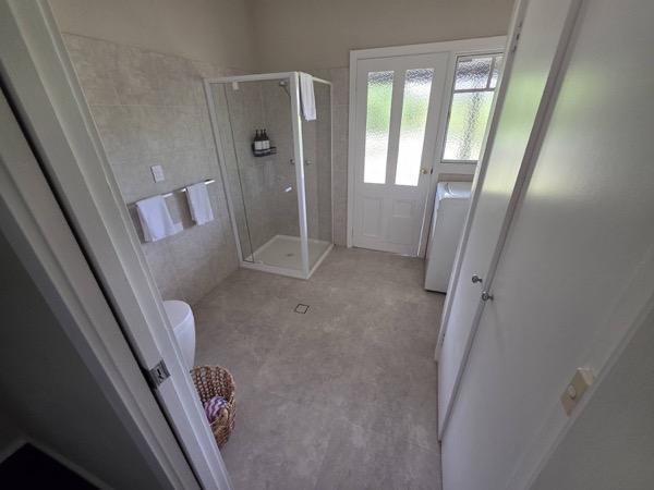 A white bathroom with a corner shower beside a glazed door
