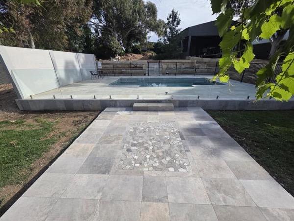 A stone path with a pebble inlay running beside a pool