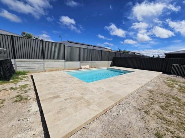 A pool with fresh stone paving laid along one side