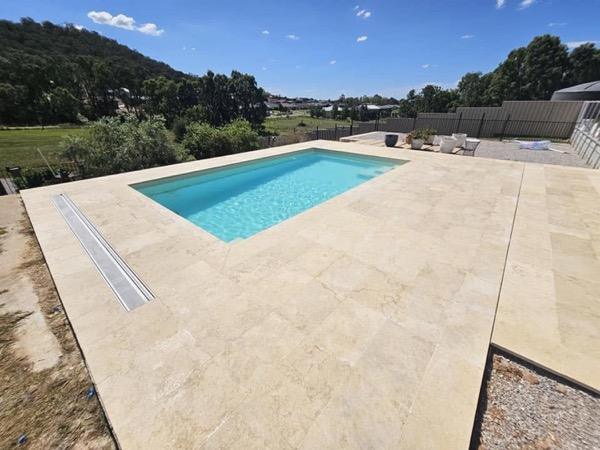 A pool set into a large paved surround with hills behind