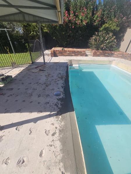 A pool part way through construction with stone coping being set