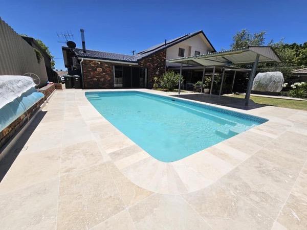 A pool with stone paving laid to a brick retaining wall