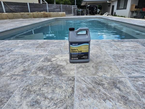A tin of sealer standing on a freshly laid stone pool surround