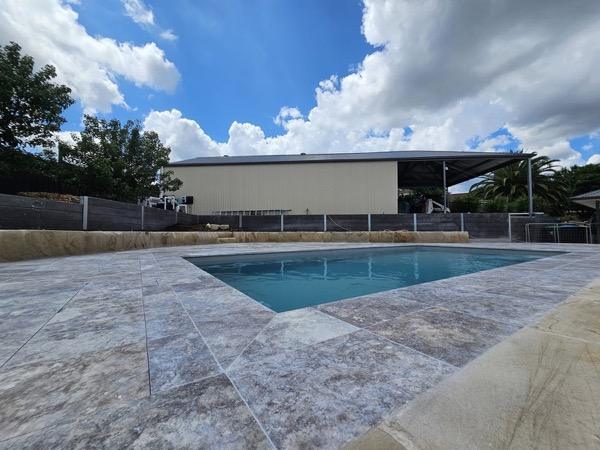 A pool set into a wide stone-paved surround under a cloudy sky